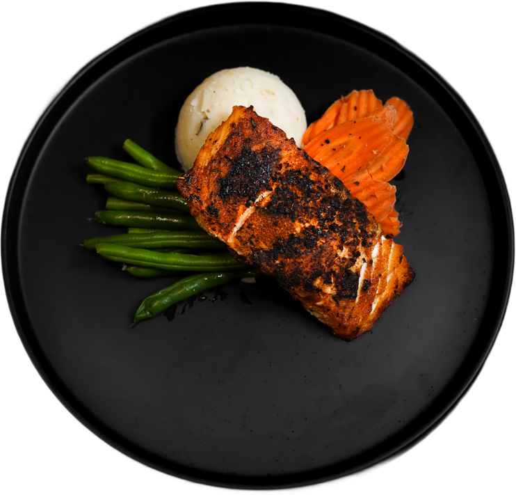 Prepared salmon, green beans, and carrots on a black plate